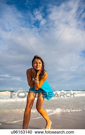 Stock Image - Young woman in sundress playing on beach, Tulum, Quintana Roo, Mexico. Fotosearch
