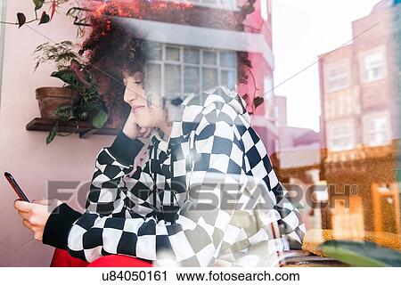 Young woman indoors, using smartphone, view through window View Large Photo Image Stock Image - Young woman indoors, using smartphone, view through window. Fotosearch