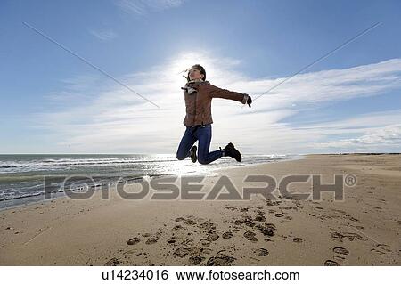 Young woman jumping mid air on beach, Tarragona, Catalonia, Spain View Large Photo Image Stock Photograph - Young woman jumping mid air on beach, Tarragona, Catalonia, Spain. Fotosearch