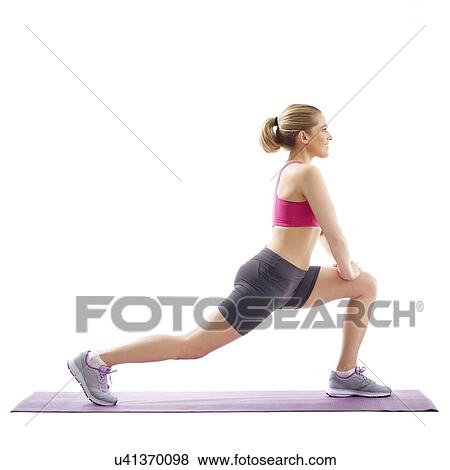 Stock Photo - Young woman lunging and stretching hip flexor, studio shot.. Fotosearch