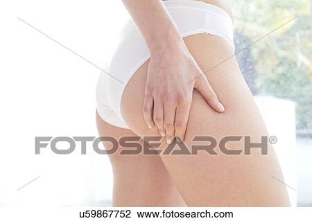 Stock Image - Young woman massaging her buttock, close up.. Fotosearch