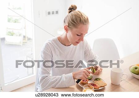 Young woman peeling kiwi fruit at breakfast table View Large Photo Image Stock Image - Young woman peeling kiwi fruit at breakfast table. Fotosearch