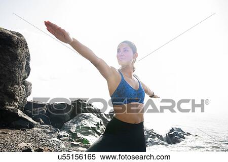 Stock Photography - Young woman practicing yoga warrior pose on beach, Las Palmas, Canary Islands, Spain. Fotosearch