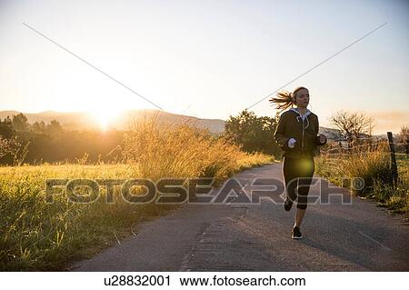 Young woman running along rural road View Large Photo Image Stock Image - Young woman running along rural road. Fotosearch