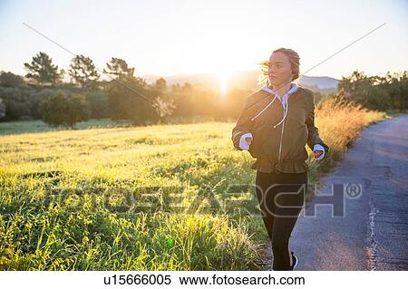 Young woman running along rural road View Large Photo Image Stock Photography - Young woman running along rural road. Fotosearch