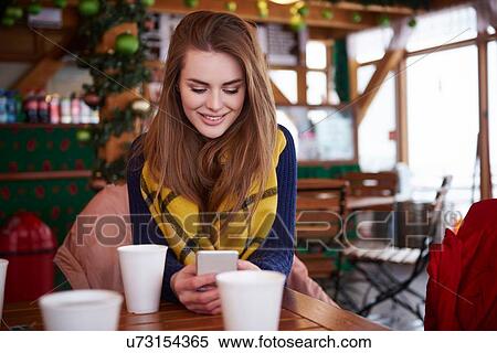 Stock Photography - Young woman smiling over text message on mobile phone. Fotosearch