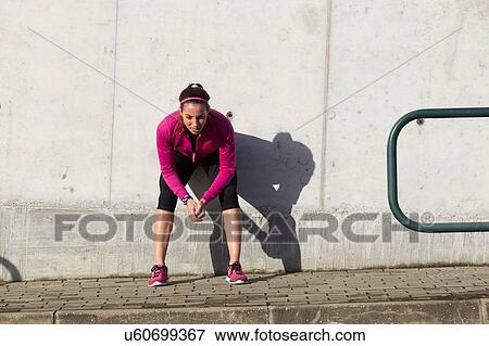 Young woman squatting against wall View Large Photo Image Stock Photo - Young woman squatting against wall. Fotosearch