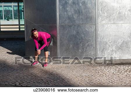 Stock Photograph - Young woman squatting against wall. Fotosearch