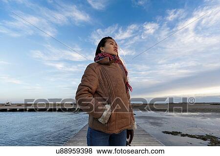 Stock Photo - Young woman standing on beach pier, Tarragona, Catalonia, Spain. Fotosearch
