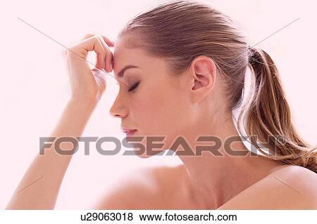 Stock Photo - Young woman touching forehead, portrait.. Fotosearch