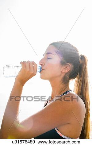 Young woman training, drinking bottled water View Large Photo Image Stock Photo - Young woman training, drinking bottled water. Fotosearch