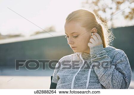 Young woman training, inserting earphones View Large Photo Image Picture - Young woman training, inserting earphones. Fotosearch