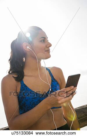 Young woman training on sea waterfront, listening to smartphone music View Large Photo Image Picture - Young woman training on sea waterfront, listening to smartphone music. Fotosearch