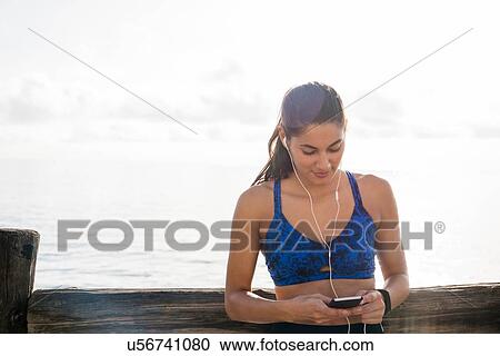 Young woman training on sea waterfront, choosing smartphone music View Large Photo Image Stock Image - Young woman training on sea waterfront, choosing smartphone music. Fotosearch