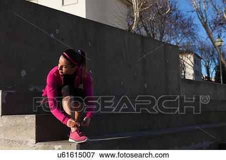 Young woman tying shoelace on training shoe, stretching legs View Large Photo Image Stock Photo - Young woman tying shoelace on training shoe, stretching legs. Fotosearch