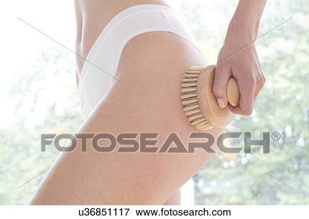 Stock Photo - Young woman using body brush, close up.. Fotosearch