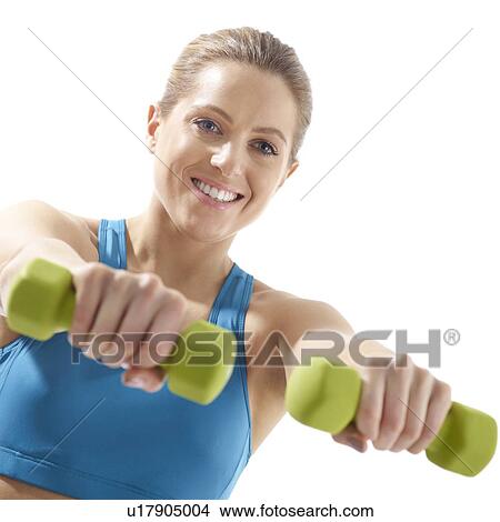 Picture - Young woman using hand weights, studio shot.. Fotosearch