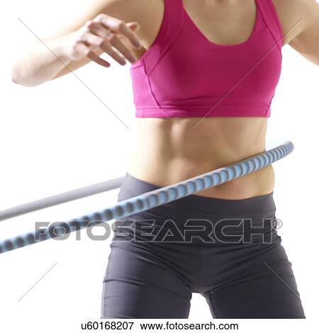 Stock Photo - Young woman using plastic hoop, studio shot.. Fotosearch