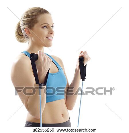 Stock Photo - Young woman using resistance band, studio shot.. Fotosearch