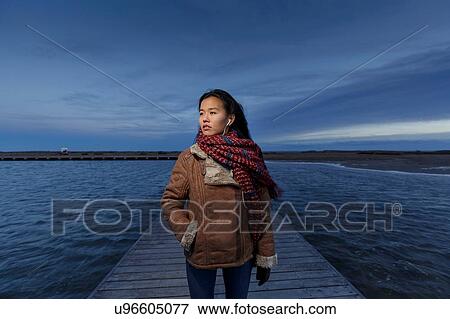 Stock Photo - Young woman walking on pier at dusk, Tarragona, Catalonia, Spain. Fotosearch