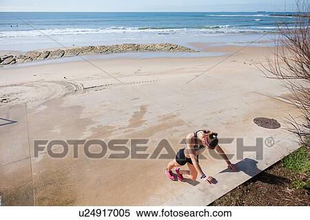 Stock Photography - Young woman warming up on beach, Carcavelos, Lisboa, Portugal, Europe. Fotosearch