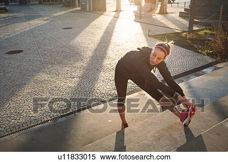 Stock Photography - Young woman warming up, stretching legs. Fotosearch