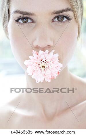 Stock Photography - Young woman with flower in her mouth, portrait.. Fotosearch