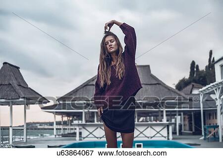 Young woman with hand on head on pier at dusk, Odessa Oblast, Ukraine View Large Photo Image Stock Photo - Young woman with hand on head on pier at dusk, Odessa Oblast, Ukraine. Fotosearch