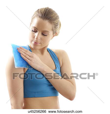 Stock Photograph - Young woman with ice pack on her shoulder, studio shot.. Fotosearch