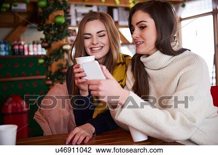 Young women smiling over text message on mobile phone View Large Photo Image Stock Image - Young women smiling over text message on mobile phone. Fotosearch