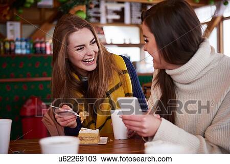 Stock Image - Young women smiling over text message on mobile phone. Fotosearch