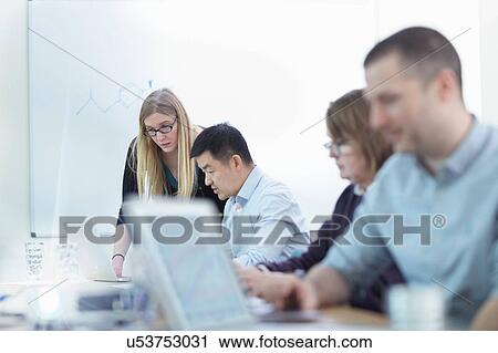 Stock Image - Younger and older scientists discussing pharmaceutical science project in meeting room. Fotosearch