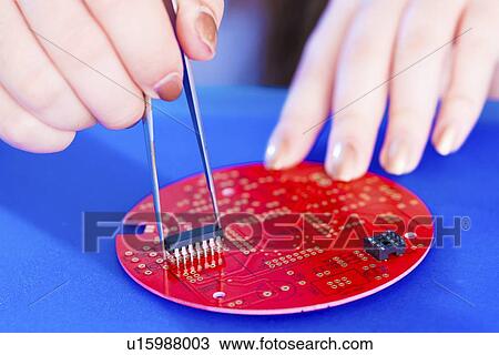 Stock Image - Adding components to printed circuit board.. Fotosearch