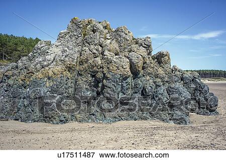 Stock Photo - Basaltic pillow lava formed from underwater volcanic activity between 500 and 600 million years ago. Photographed at Newborough Sands, Anglesey, Wales, UK.. Fotosearch