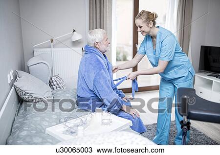 Care worker helping senior man to put on dressing gown. View Large Photo Image Stock Image - Care worker helping senior man to put on dressing gown.. Fotosearch