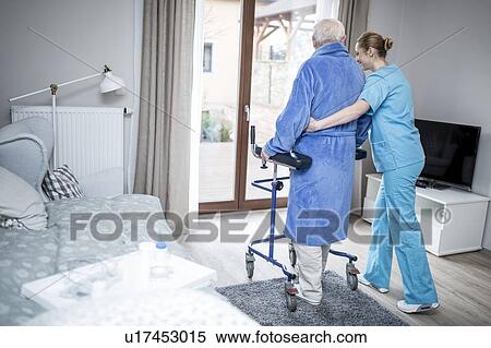 Stock Photography - Care worker helping senior man to walk with a rollator.. Fotosearch