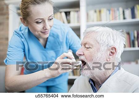 Care worker helping senior man with inhaler. View Large Photo Image Picture - Care worker helping senior man with inhaler.. Fotosearch