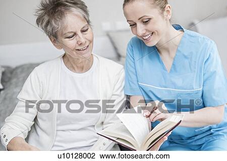 Care worker reading book with senior woman in care home. View Large Photo Image Stock Image - Care worker reading book with senior woman in care home.. Fotosearch