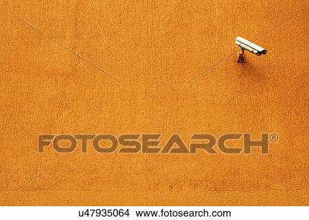Picture - CCTV camera on orange wall.. Fotosearch