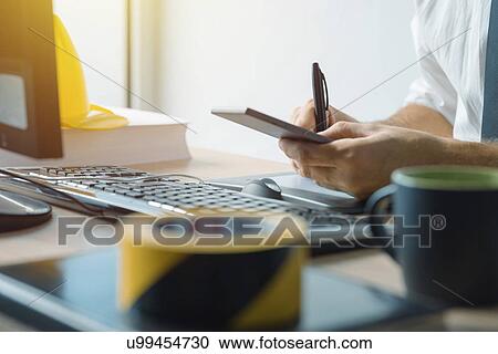 Stock Image - Civil engineer using smartphone in office.. Fotosearch