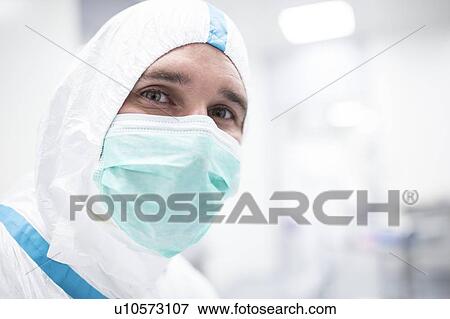 Stock Photo - Close-up of a lab technician wearing a protective suit and face mask in a laboratory that must maintain a sterile environment.. Fotosearch