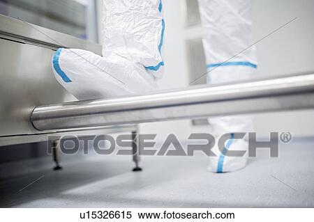 Stock Photography - Close-up of a technician walking through a decontamination cabin before entering a sterile laboratory.. Fotosearch