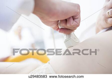 Stock Image - Close-up of a woman having an ultrasound scan of her abdomen.. Fotosearch