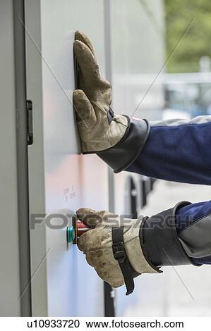 Stock Image - Close-up of an engineer closing steel enclosure door.. Fotosearch