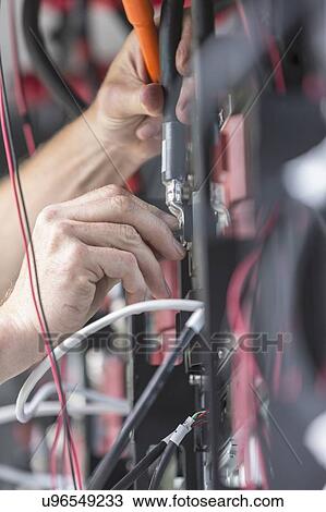 Stock Image - Close-up of an engineer connecting up power cable in an industrial backup facility.. Fotosearch