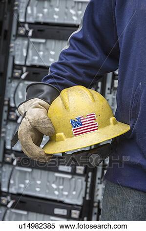 Stock Photography - Close-up of an engineer wearing rubber protective gloves and carrying hard hat with US flag on it.. Fotosearch