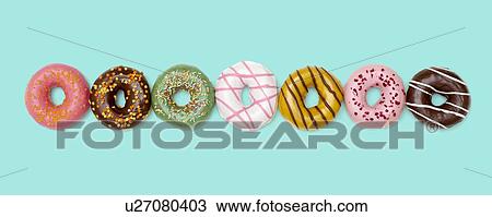 Stock Image - Colourful doughnuts in a row, studio shot.. Fotosearch