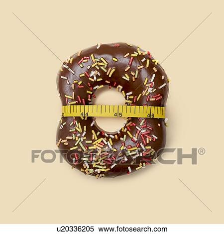 Stock Photography - Dieting, conceptual image. Chocolate doughnut with sugar strands and tape measure, studio shot.. Fotosearch