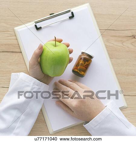 Doctor advising an apple instead of pills and antibiotics, conceptual image. View Large Photo Image Stock Image - Doctor advising an apple instead of pills and antibiotics, conceptual image.. Fotosearch