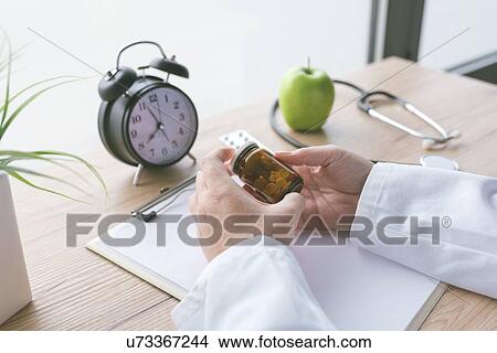 Doctor holding unlabelled bottle of pills. View Large Photo Image Picture - Doctor holding unlabelled bottle of pills.. Fotosearch